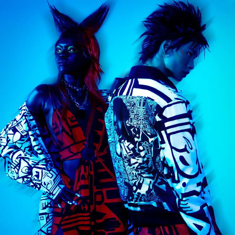 Editorial duo in BAM-BAM red abstract dress and black-white jacket—artistic streetwear.