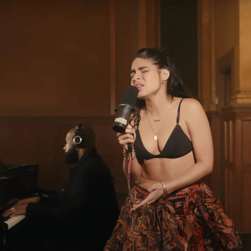 Singer performing in a BAM-BAM brown-black abstract skirt—wearable art streetwear on stage.