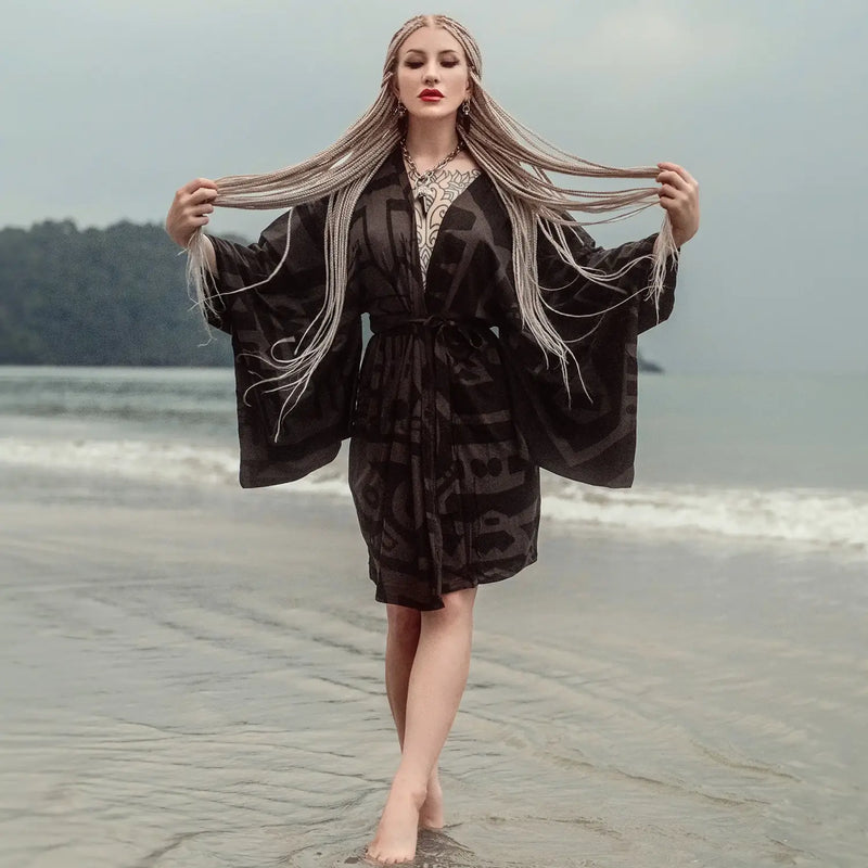Model in BAM-BAM black tonal abstract-print kimono robe, barefoot at the beach—sustainable streetwear.