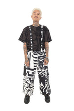 Male model in BAM-BAM black and white overalls with bold graphic print and black t-shirt, front view.