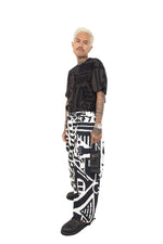 Model showcasing BAM-BAM abstract black and white overalls with suspenders, side angle.