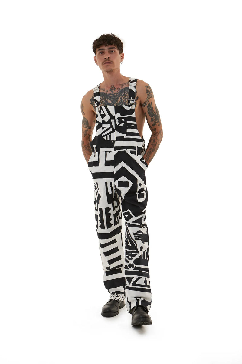 Male model with tattoos wearing black and white BAM‑BAM dungarees featuring cubist patternism and self‑expression