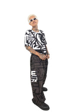 Model leaning wearing charcoal BAM‑BAM baggy pants demonstrating self‑expression