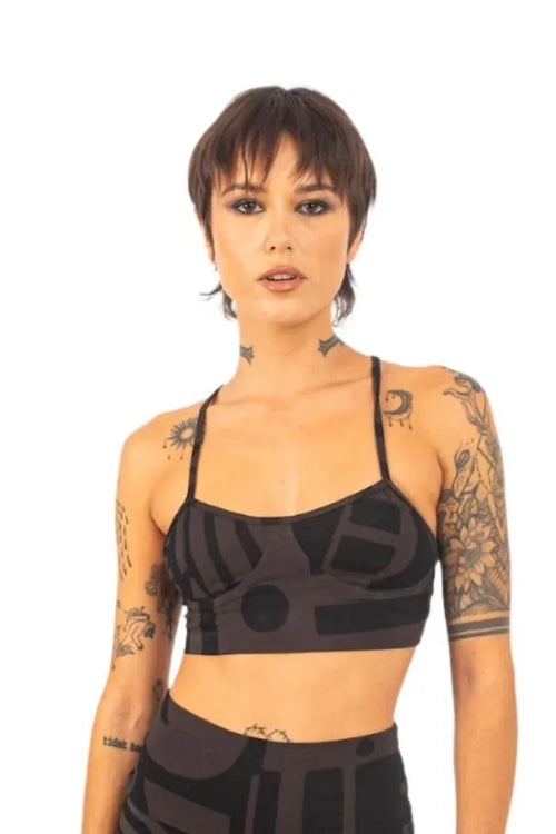 Model with tattoos wearing charcoal black BAM‑BAM bra top and baggy pants, showcasing wearable art