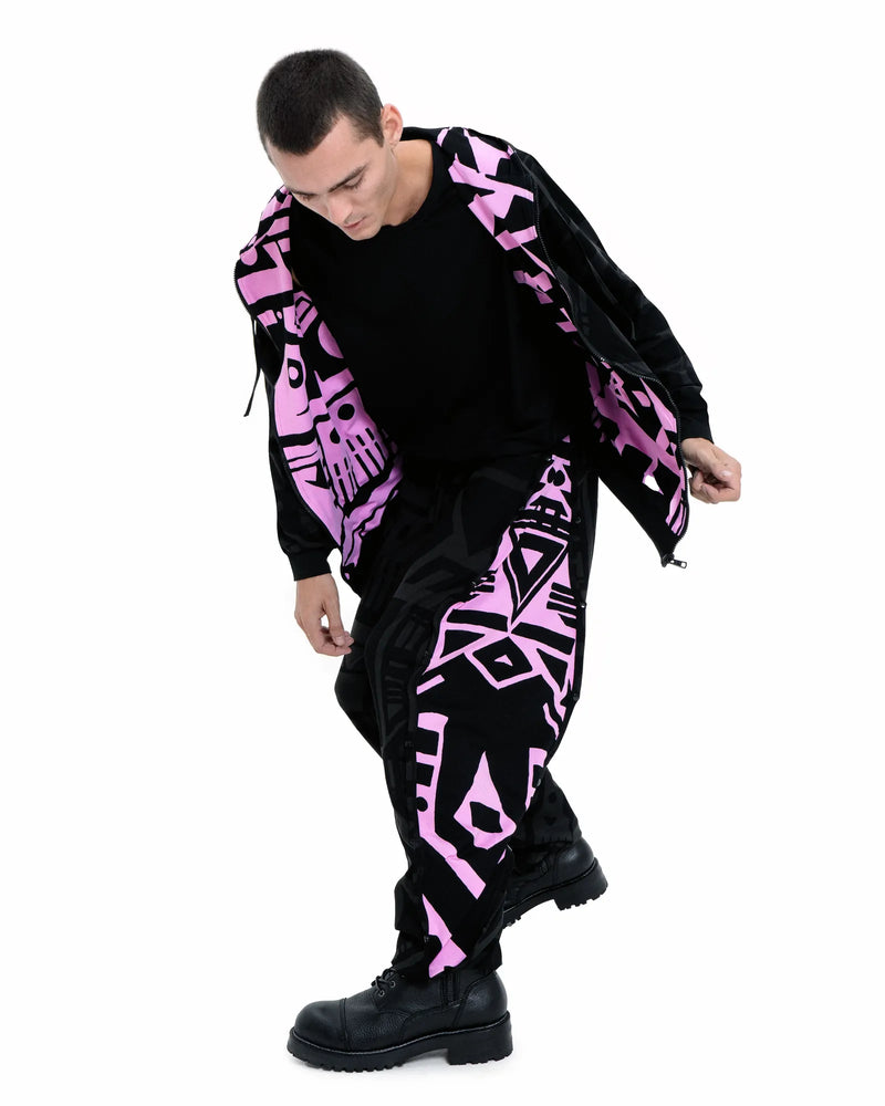 Model seated wearing BAM‑BAM charcoal and pink poppa pants and bra top, featuring abstract prints