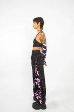 Model spinning in charcoal and pink BAM‑BAM poppa pants capturing wearable art and cubist patternism