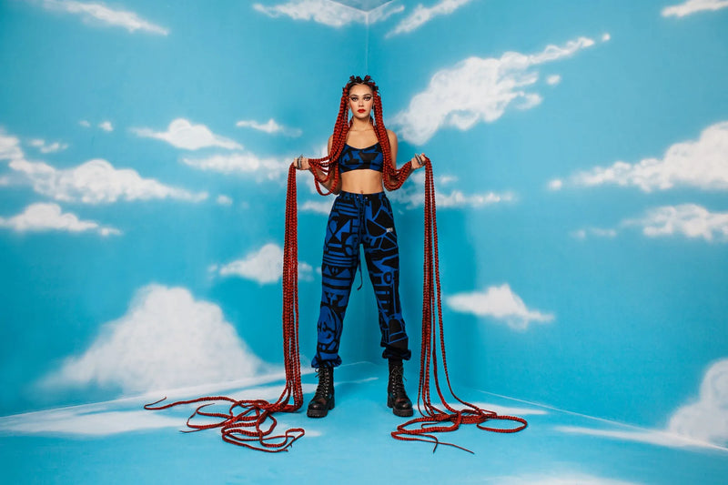 Model in studio wearing dark blue BAM‑BAM trousers and black boots for bold self‑expression