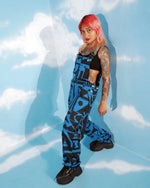 Model posing with arms raised wearing dark blue dungarees by BAM‑BAM expressing bold self‑expression