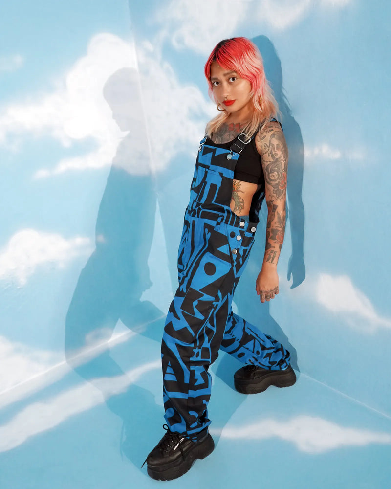 Model posing with arms raised wearing dark blue dungarees by BAM‑BAM expressing bold self‑expression
