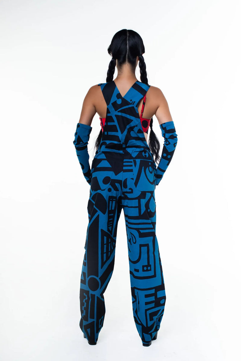 Model standing in dark blue BAM‑BAM dungarees and black boots, highlighting wearable art and cubist patternism